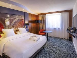 a hotel room with a large bed and a chair at Hotel Mercure Toulouse Centre Compans in Toulouse