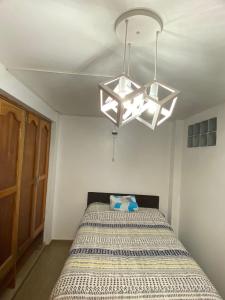 a bedroom with a bed and a chandelier at Warm and Modern in the heart of the city in Huaraz