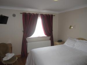 a bedroom with a bed and a window with red curtains at Cuil Darach in Cluain Eois