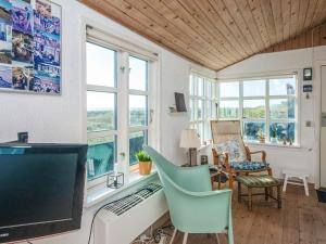 a living room with a tv and chairs and windows at 4 person holiday home in Grenaa in Grenå