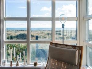 a chair in front of a window looking out at the ocean at 4 person holiday home in Grenaa in Grenå