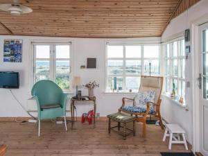 a living room with chairs and a tv and windows at 4 person holiday home in Grenaa in Grenå