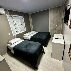 a bedroom with two beds and a window at Loft Lux 11 Centro in Chapecó