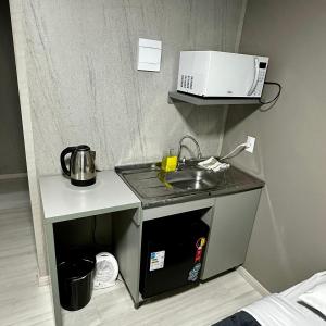 a small kitchen with a sink and a microwave at Loft Lux 11 Centro in Chapecó