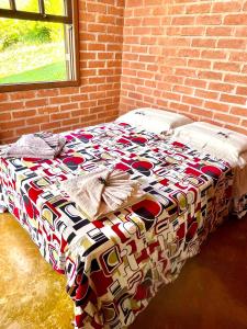 een bed in een kamer met een bakstenen muur bij Abrigo de montanha - Berghütte in São Bento do Sapucaí