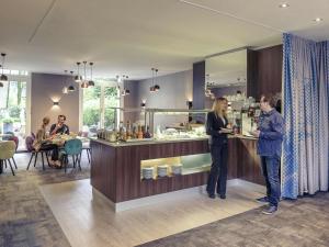two people standing at a counter in a restaurant at Mercure München am Olympiapark in Munich