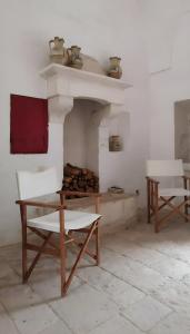 een kamer met 2 witte stoelen en een open haard bij La Posta dell'Eremo in Ostuni