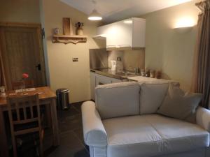 uma sala de estar com um sofá e uma cozinha em The Potting Shed em Little Torrington