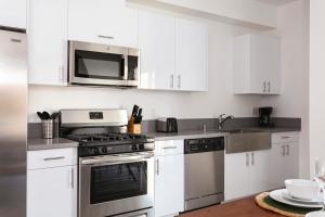 a kitchen with white cabinets and stainless steel appliances at Experience Luxury 4BR Townhouse Sleeps 8 with Parking in Los Angeles