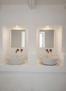 twee wastafels in een witte badkamer met twee spiegels bij La Posta dell'Eremo in Ostuni