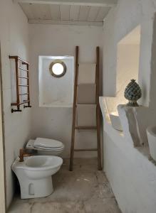 een witte badkamer met een toilet en een wastafel bij La Posta dell'Eremo in Ostuni +2 foto's