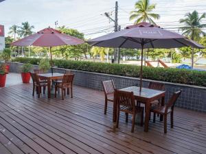 two tables and chairs with umbrellas on a deck at ibis Maceio Pajuçara in Maceió