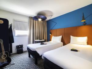 a hotel room with two beds and a guitar at ibis Paris porte de Bercy in Charenton-le-Pont +38 photos
