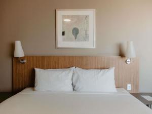 Una cama con almohadas blancas en una habitación de hotel. en Mercure Sydney Parramatta, en Sídney