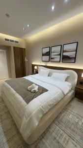 a large white bed in a bedroom with three pictures on the wall at Luxury apartment with full sea view in Jeddah
