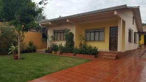 a small yellow house with a green yard at Yolanda Family House in Foz do Iguaçu