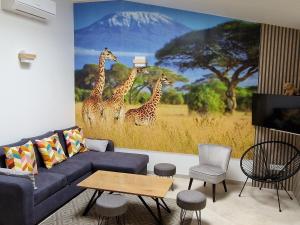 a living room with a mural of giraffes at Maison de charme en bord du Loir, 6-8 pers, proche Zoo de La Flèche, piscine à venir, parking inclus - FR-1-410-429 in La Flèche