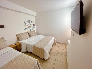 a room with two beds and a flat screen tv at Pousada Solana in Salvador