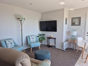 a living room with a couch and chairs and a flat screen tv at Seaviews on Sullivans in Paihia