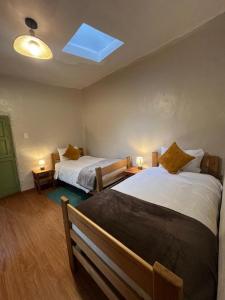 a bedroom with two beds and a window on the ceiling at Casa Terra in Cusco