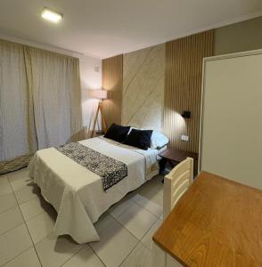 a bedroom with a bed and a table in it at Paraná Suite Alem in Paraná