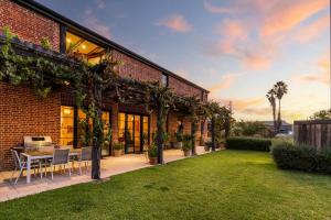 a brick house with a patio with a table and chairs at The Warehouse - Heritage Elegance in Central Mudgee in Mudgee