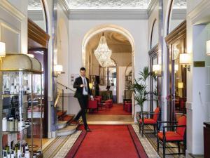 a man in a suit walking through a lobby at Carlton Hotel Lyon - MGallery Collection in Lyon