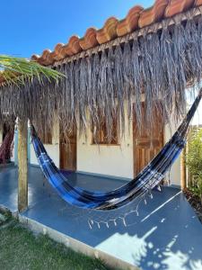 a hammock outside of a house with a thatched roof at Dona Canoa Hospedaria in Porto Seguro +1 photo