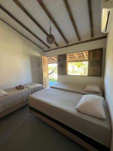 two beds in a room with two windows at Dona Canoa Hospedaria in Porto Seguro
