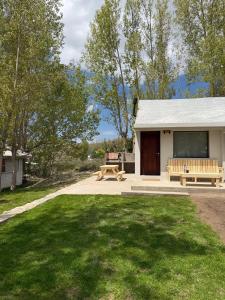 a white building with a picnic table and a bench at Cabañas boutique Huella Andina in Potrerillos