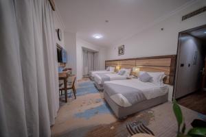 a hotel room with two beds and a table at فندق سبال الماسي الإشراق سابقا -sebal almasi hotel in Al Madinah