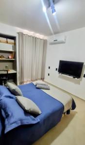 a bedroom with a bed with blue sheets and a tv at Quarto Vista Mar in Recife