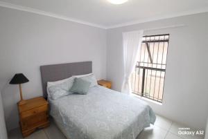 a white bedroom with a bed and a window at 87 on Sunbird in Langebaan