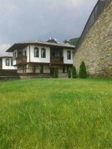 une maison avec une grande pelouse à côté d'un mur dans l'établissement Leshtenski Perli, à Leshten