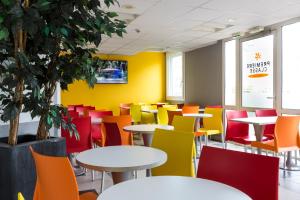 una cafetería de colores vivos con mesas y sillas en Premiere Classe Roissy Aéroport Charles De Gaulle en Roissy-en-France