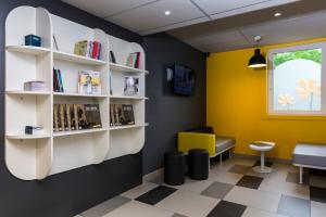 uma sala de espera com paredes amarelas e prateleiras brancas em Premiere Classe Roissy Aéroport Charles De Gaulle em Roissy-en-France