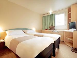 a hotel room with two beds and a television at Hotel ibis Leiria Fatima in Leiria