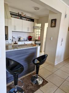 サンタ・ローザにある1 dorm privativo casalのカウンター前の黒いスツール2脚付きキッチン