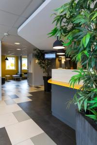 un hall de bureau avec un comptoir et des plantes en pot dans l'établissement Premiere Classe Roissy Aéroport Charles De Gaulle, à Roissy-en-France