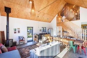a living room with a wooden ceiling and a staircase at The Black Barn - Karitane Beach in Karitane