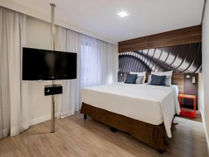 a bedroom with a large bed and a flat screen tv at Mercure Sao Paulo Moema Times Square in Sao Paulo