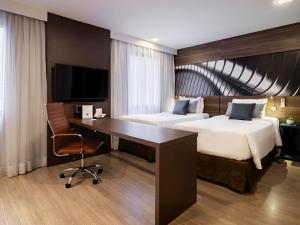 a hotel room with two beds and a desk at Mercure Sao Paulo Moema Times Square in Sao Paulo +190 photos