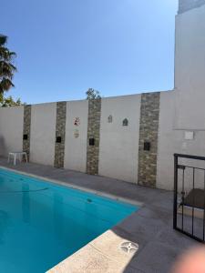 a swimming pool with blue water in front of a wall at Quincho Los Abuelos in Chivilcoy