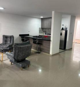 a living room with two chairs and a kitchen at posada la hermosa in Santa Rosa de Cabal