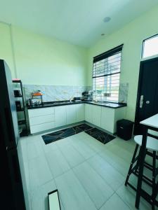 a kitchen with white cabinets and a tile floor at WanZa House in Bachok