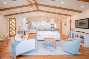 a living room with white furniture and a kitchen at The Emerald Surf House I home in Waialua