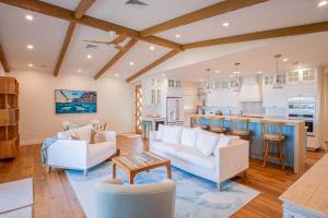 a living room with white furniture and a kitchen at The Emerald Surf House I home in Waialua