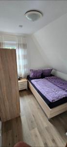 a bedroom with a bed with a purple comforter at Monteurs-Ferienwohnung in Emden