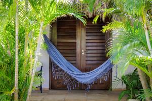 a hammock in front of a house with palm trees at Controvento Boutique Hotel - Yoga Kitesurf in Cumbuco +24 photos
