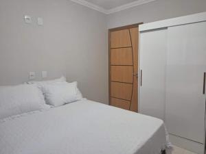 a bedroom with a white bed and a wooden cabinet at Ap 440 m do mar, próx Beto Carrero in Navegantes